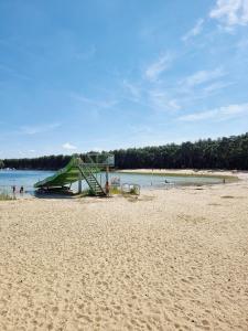 una playa de arena con parque infantil y agua en Camping Siësta, en Lille