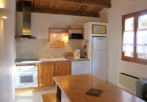cocina con armarios de madera y nevera blanca en Domaine Le Mayne - Le Châtaignier - Clévacances 2 Clés, en Blanquefort-sur-Briolance