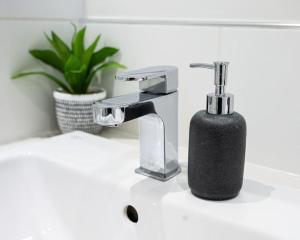a bathroom sink with a soap dispenser next to a faucet at Contemporary 1 Bed Apartment in Bedford
