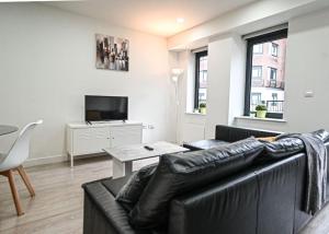 a living room with a black leather couch and a table at Contemporary 1 Bed Apartment in Bedford