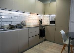 a kitchen with white cabinets and a sink and a table at Contemporary 1 Bed Apartment in Bedford