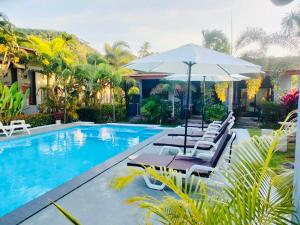a swimming pool with lounge chairs and an umbrella at Andawa Lanta Resort in Ko Lanta