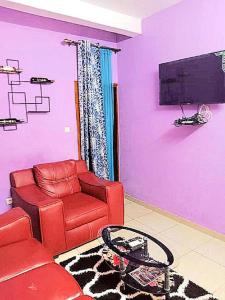 a living room with a red couch and a tv at Residence Sighaka - Studio Meublé VIP avec WiFi, Gardien, Parking in Douala