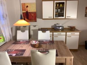 cocina con mesa de madera y armarios blancos en NEU! Ferienhaus Zur Oste en Hechthausen