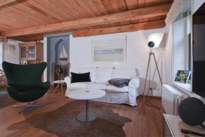 sala de estar con sofá blanco y silla verde en Kate 60 - Suite Twee, en Borkum