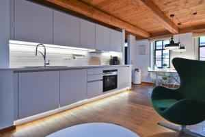a kitchen with white cabinets and a green chair at Kate 60 - Suite Twee in Borkum