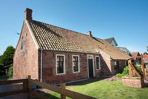 una casa de ladrillo con una valla delante de ella en Kate 60 - Suite Twee, en Borkum