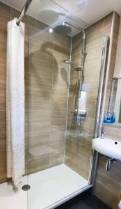 a shower with a glass door next to a sink at Tom's Place in Kirkcudbright