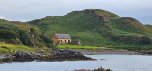 a house on a hill next to a body of water at Doune Bay Lodge 