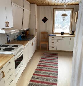 una cucina con armadi bianchi e un tappeto sul pavimento di Cozy cottage on a large natural plot in lovely Harjedalen a Vemdalen