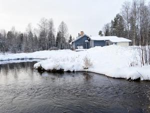 a house is covered in snow next to a river at Cozy cottage on a large natural plot in lovely Harjedalen in Vemdalen