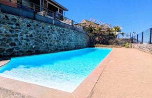 een blauw zwembad naast een stenen muur bij Le Sable Blanc -T2 à la Saline avec piscine in La Saline les Bains