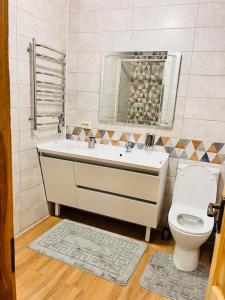 La salle de bains est pourvue d'un lavabo blanc et de toilettes. dans l'établissement Котедж Golden Lemon, à Mijgiria