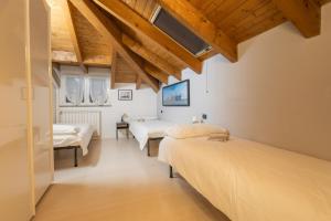 two beds in a room with wooden ceilings at Bnbook Bilo Conciliazione in Rho