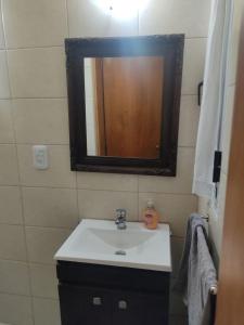 een badkamer met een wastafel en een spiegel bij Complejo Berazategui in Villa D. Sobral