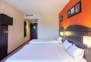 カステルキュリエにあるB&B HOTEL Agen Castelculierのオレンジ色の壁の客室で、ベッド2台が備わります。