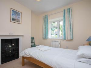 a bedroom with a white bed and a fireplace at 3 Bed in Portesham DC181 in Portesham