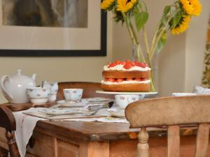 uma mesa com um bolo e um vaso com flores em 2 Bed in Hartington 75637 em Hartington