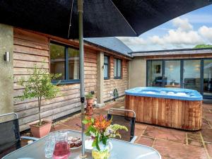 a patio with a hot tub and a table with an umbrella at 2 Bed in Okehampton 75708 in Sampford Courtenay