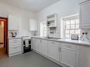 a white kitchen with white cabinets and a sink at 1 Bed in Alness CA015 in Boath