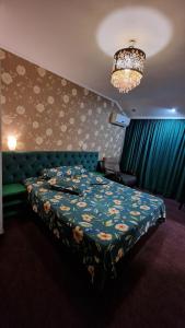 1 dormitorio con cama y lámpara de araña en Pensiunea Toma en Ploieşti
