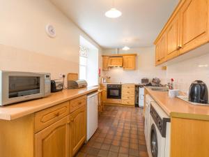 cocina con armarios de madera y microondas en 2 Bed in Applecross CA422, en Applecross