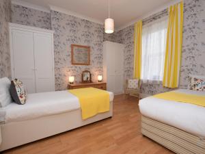 1 dormitorio con 2 camas y cortinas amarillas en 2 Bed in Ventnor 75730, en Ventnor