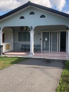 uma casa branca com colunas e janelas em Easah Homestay Malacca em Malaca