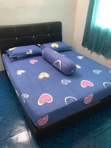 uma cama com um edredão azul e almofadas em Easah Homestay Malacca em Malaca