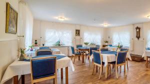 a dining room with tables and blue chairs at Pension Wosmaaren in Norddorf