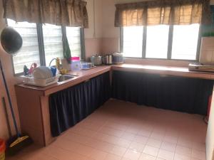 uma cozinha com um balcão e um lavatório e duas janelas em Easah Homestay Malacca em Malaca