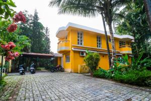una casa amarilla con dos motos estacionadas frente a ella en Lemon Zest Oasis By JadeCaps Pvt Pool 6BHK Goa en Nuvem