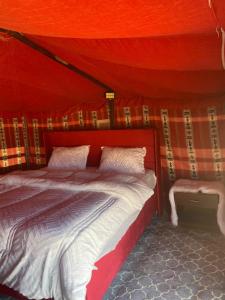 a bed in a room with a red tent at Clouds Desert Camp in Bidiyah