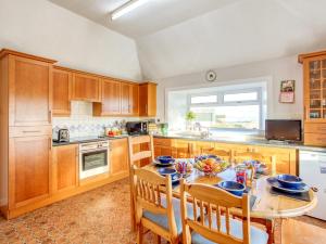 una cucina con armadi in legno, tavolo e sedie di 3 bed property in Castletown CA416 a Castletown