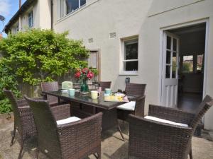 um pátio com uma mesa com cadeiras e flores em 3 Bed in Cerne Abbas 74803 em Cerne Abbas