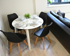 a white table with black chairs and a couch at Chic 1 Bedroom Flat in Bedford