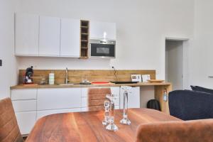 cocina con mesa de madera y armarios blancos en Le Liégeois - proche centre - Maison de maître, en Lieja