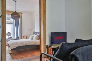 a bedroom with a bed and a television in a mirror at Le Liégeois - proche centre - Maison de maître in Liège