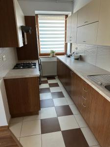 a kitchen with wooden cabinets and a checkered floor at Apartament Wałbrzych in Wałbrzych +6 photos