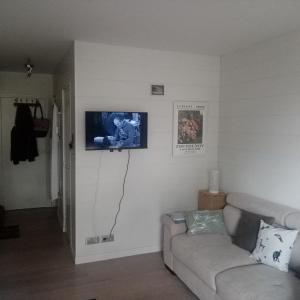 uma sala de estar com um sofá e uma televisão na parede em Les Hortensias em Bénodet