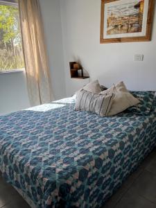 a bedroom with a bed with a quilt and a window at Firenze Cabañas - Playa Chapadmalal in Chapadmalal