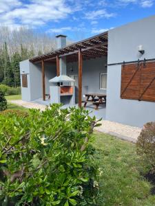 a white house with a grill in the yard at Firenze Cabañas - Playa Chapadmalal in Chapadmalal