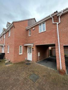 un bâtiment en briques avec un garage et une allée. dans l'établissement The Belfry 3 Bedrooms 2 Bathrooms Contractors & Family, à Higham Ferrers