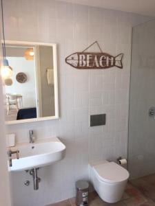 un baño con lavabo y una señal de pescado en la pared en Hoso Loft 24 Beach House en Costa da Caparica