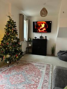 un árbol de Navidad en una sala de estar con chimenea en The Belfry 3 Bedrooms 2 Bathrooms Contractors & Family en Higham Ferrers