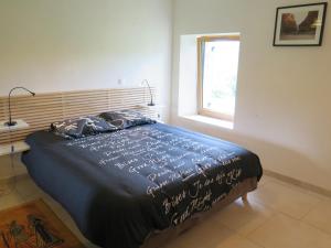 ein Schlafzimmer mit einem Bett mit blauer Decke und einem Fenster in der Unterkunft Domaine du Mayne - La Ferme - Clévacances 3 clés in Blanquefort-sur-Briolance