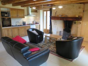 ein Wohnzimmer mit Ledermöbeln und einem Kamin in der Unterkunft Domaine du Mayne - La Ferme - Clévacances 3 clés in Blanquefort-sur-Briolance