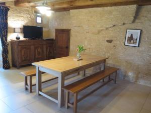 een eetkamer met een houten tafel en banken bij Domaine du Mayne - La Ferme - Clévacances 3 clés in Blanquefort-sur-Briolance