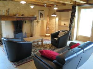 een woonkamer met een leren bank en stoelen en een open haard bij Domaine du Mayne - La Ferme - Clévacances 3 clés in Blanquefort-sur-Briolance