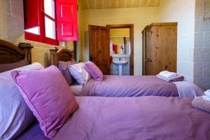 1 dormitorio con 2 camas con almohadas moradas en Amaryllis Holiday Home, en Qala